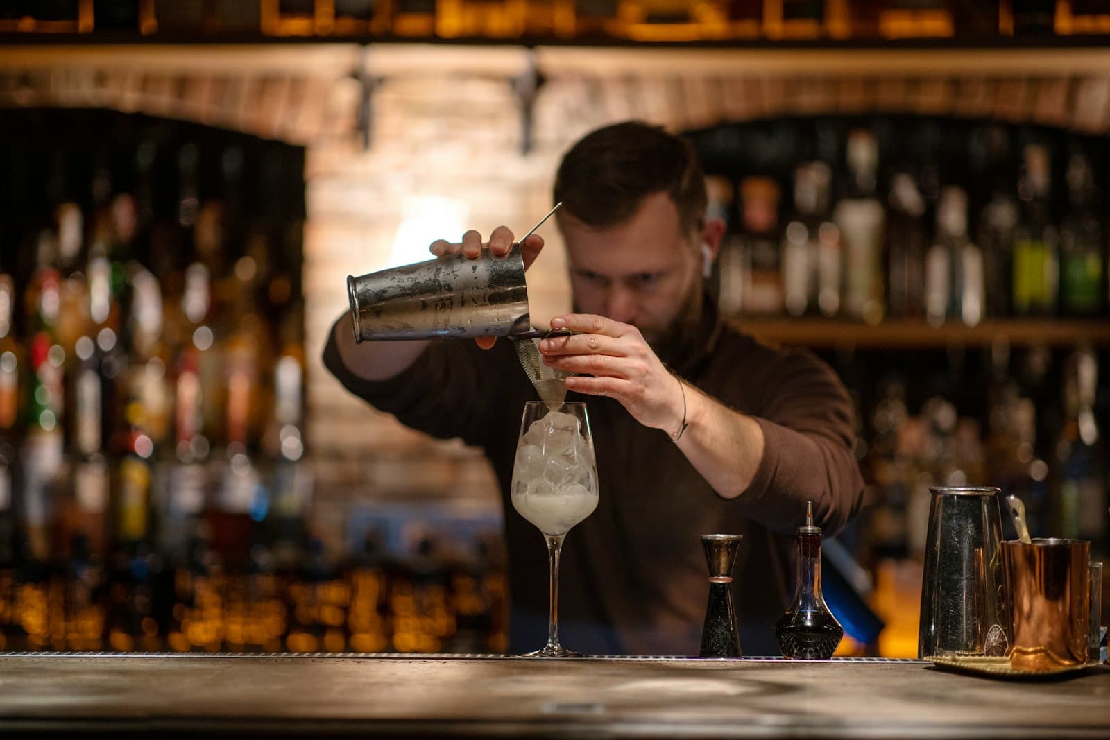 Une personne prépare un verre derrière le bar
